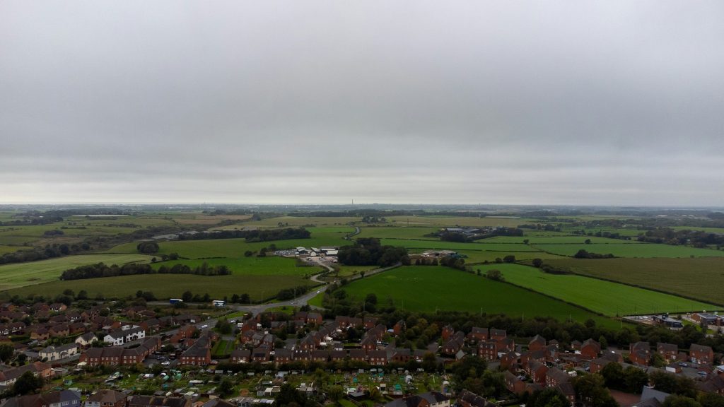 Aerial view of a residential development bordering farmland near Preston, Lancashire