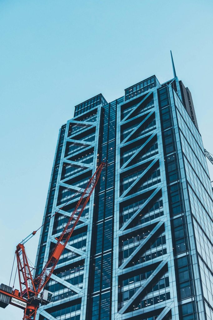 Crane in front of a blue steel-framed tower in London